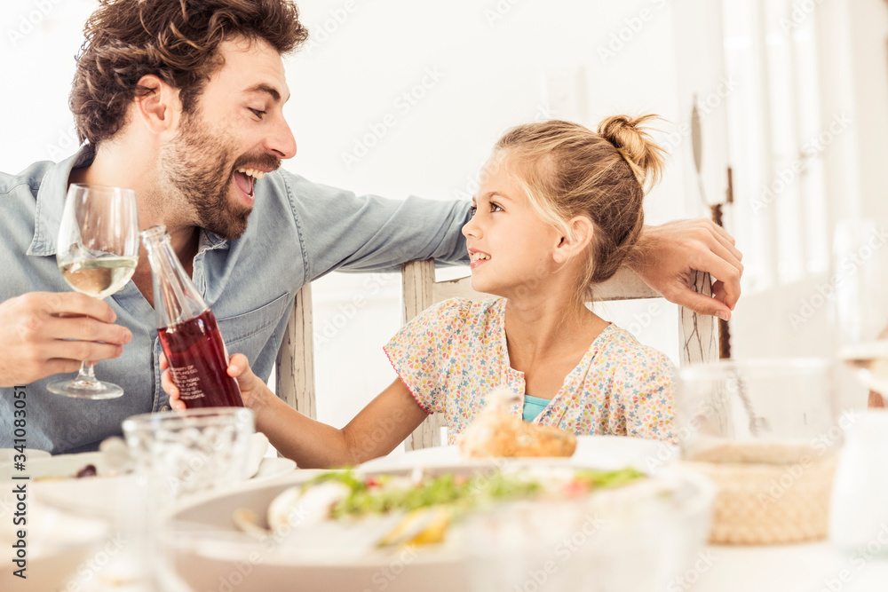 Father and daughter sitting at dining table toasting Father and daughter sitting at dining table toasting