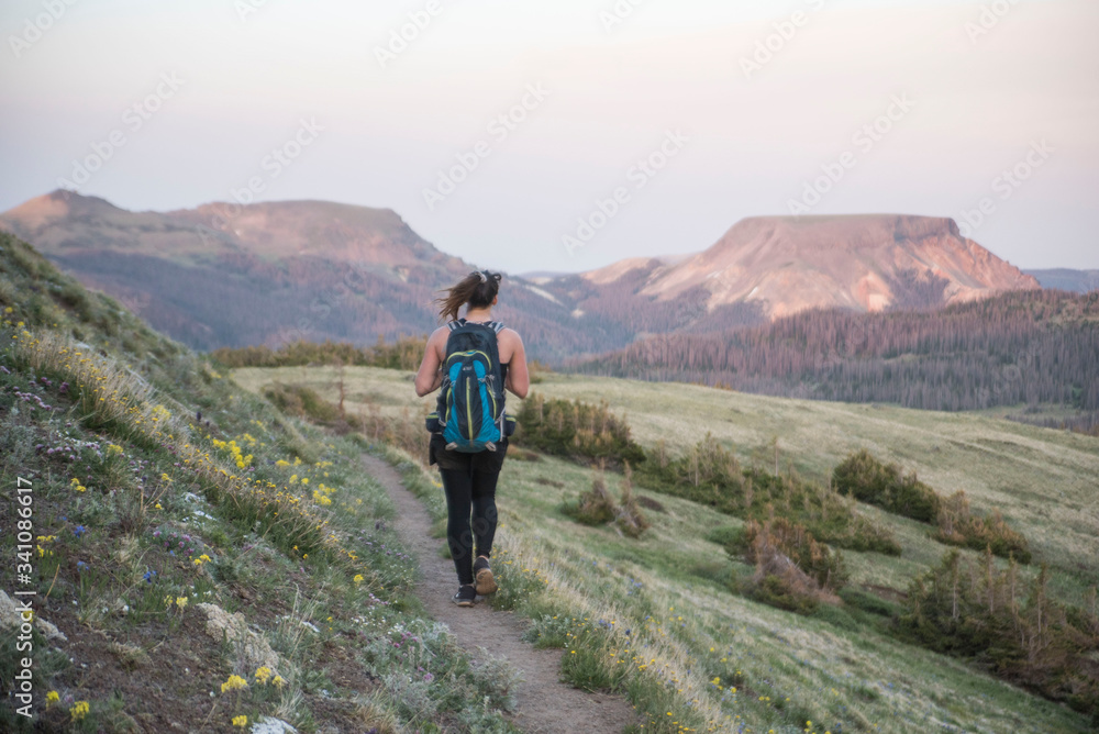 female traveler and photographer hiking in the mountains of Colorado at sunset