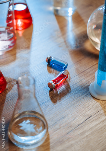 What will you choose red or blue medicine? Vaccines are lying on a table in a laboratory among tubes and flasks with different liquids.