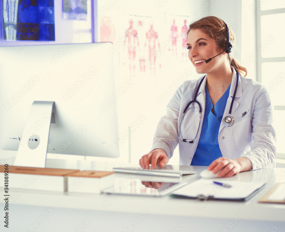 Young practitioner doctor working at the clinic reception desk, she is answering phone calls and scheduling appointments Young practitioner doctor working at the clinic reception desk, she is answering phone calls and scheduling appointments