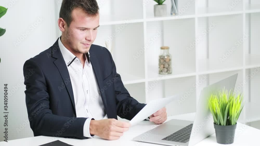 Young man working with documents in office at desk Young man working with documents in office at desk