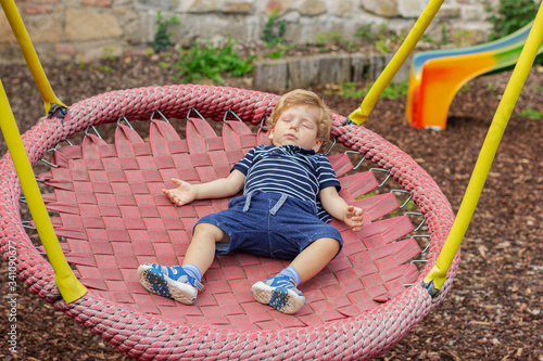 Wallpaper Mural Sleepy child riding on a swing. Summer. Little boy sleeps outdoors. The kid is tired. Torontodigital.ca