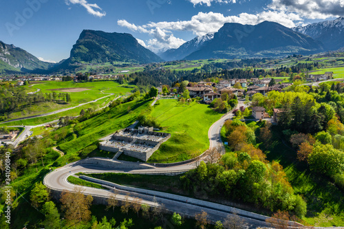 Aerial view of valley Cares, Trentino, green slopes of the mountains of Italy, huge clouds over a valley, roof tops of houses, Dolomites on background, bridges, river and roads, spring colors photo