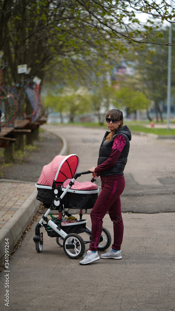 Young mother with a pram in the park Young mother with a pram in the park