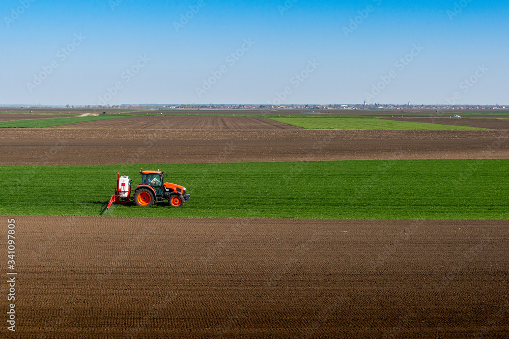 Obraz premium Tractor spraying wheat in field