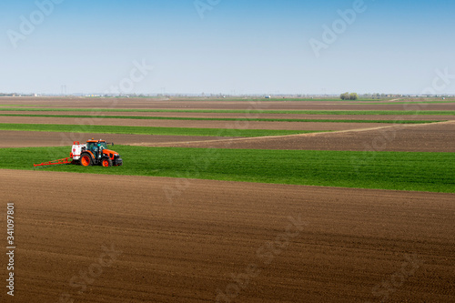 Tractor spraying wheat in field © Vesna