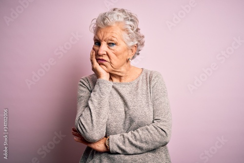 Senior beautiful woman wearing casual t-shirt standing over isolated pink background thinking looking tired and bored with depression problems with crossed arms.
