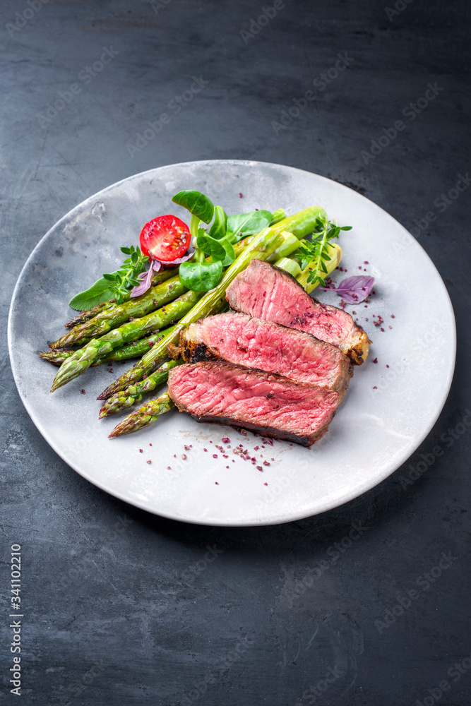 Barbecue dry aged wagyu entrecote beef steak with lettuce and green asparagus as closeup on a modern design plate Barbecue dry aged wagyu entrecote beef steak with lettuce and green asparagus as closeup on a modern design plate