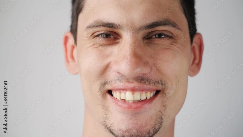 portrait Beautiful Caucasian young man smiling at the camera. Happy men's emotions on a white background. Slow motion portrait Beautiful Caucasian young man smiling at the camera. Happy men's emotions on a white background. Slow motion
