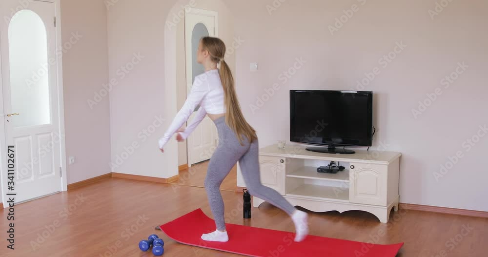 Fit young girl training at home. Beautiful female athlete working out for well being in domestic gym, training legs muscles doing lunges exercise