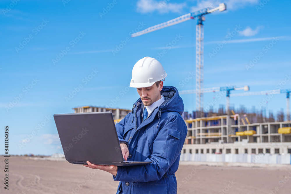 civil engineer in a white helmet looking documents on the background of construction civil engineer in a white helmet looking documents on the background of construction