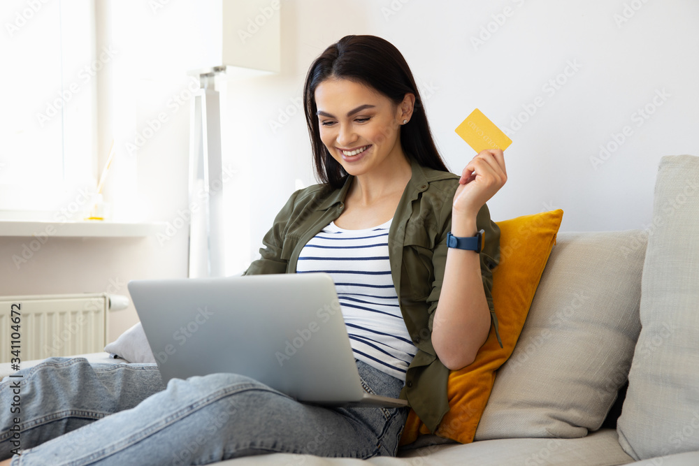 Charming lady using laptop and holding gold card Charming lady using laptop and holding gold card