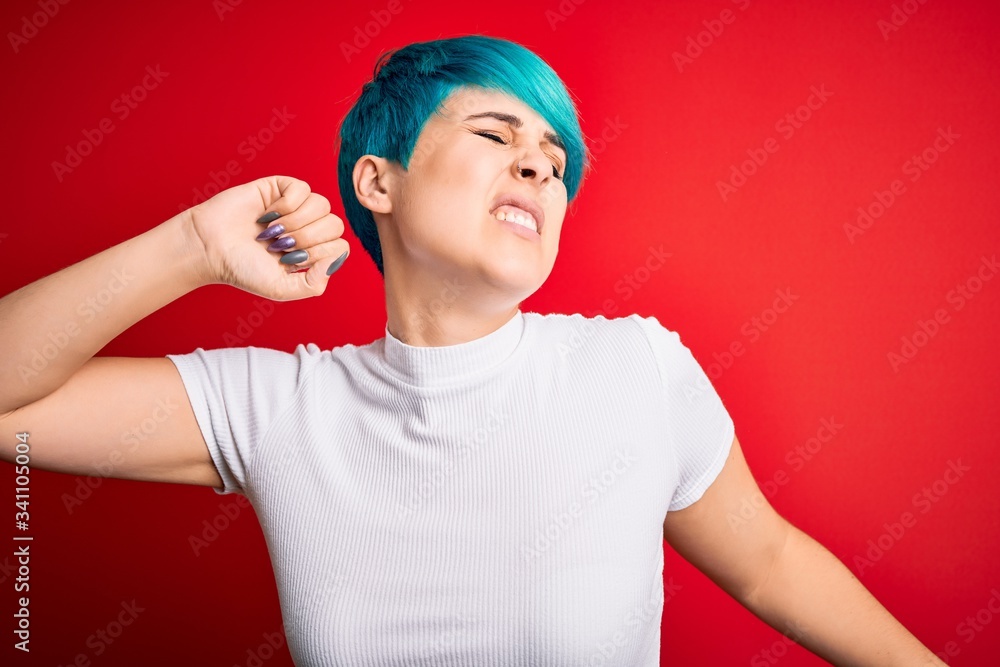 Young beautiful woman with blue fashion hair wearing casual t-shirt over red background stretching back, tired and relaxed, sleepy and yawning for early morning Young beautiful woman with blue fashion hair wearing casual t-shirt over red background stretching back, tired and relaxed, sleepy and yawning for early morning