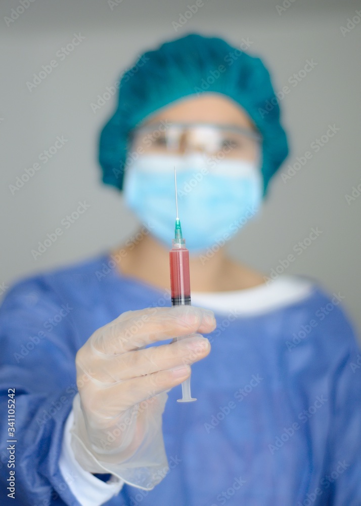 Mano de un médico mujer, doctora o enfermera con análisis de sangre en una jeringa, portando equipo de protección, tapabocas o mascara facial, gafas de seguridad y guantes. Mano de un médico mujer, doctora o enfermera con análisis de sangre en una jeringa, portando equipo de protección, tapabocas o mascara facial, gafas de seguridad y guantes.