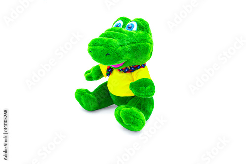 Plush soft, green, children's crocodile toy isolated on a white background with shadow reflection. Side view, front view. The beautiful doll is dressed in a yellow t-shirt and a colorful scarf.