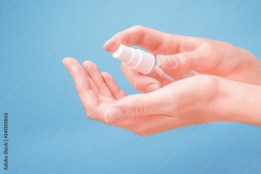 Hands cleaning on blue background. Closeup of hand disinfecting concept. Hands cleaning from virus, bacteria, germs with alcohol decontaminating agent. Personal hygiene concept. Cleaning hands concept