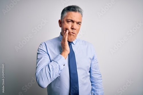 Middle age handsome grey-haired business man wearing elegant shirt and tie touching mouth with hand with painful expression because of toothache or dental illness on teeth. Dentist