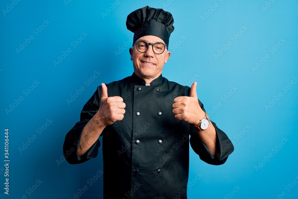 Middle age handsome grey-haired chef man wearing cooker uniform and hat success sign doing positive gesture with hand, thumbs up smiling and happy. Cheerful expression and winner gesture. Middle age handsome grey-haired chef man wearing cooker uniform and hat success sign doing positive gesture with hand, thumbs up smiling and happy. Cheerful expression and winner gesture.