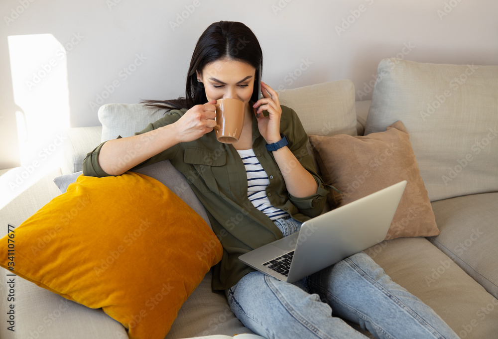 Charming lady using laptop and talking on cellphone at home Charming lady using laptop and talking on cellphone at home