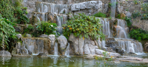Tropical background with waterfall and green leaves.