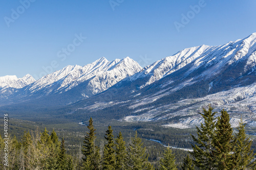 close-up view of the mountain peak with trees and snow on it sunny spring day.