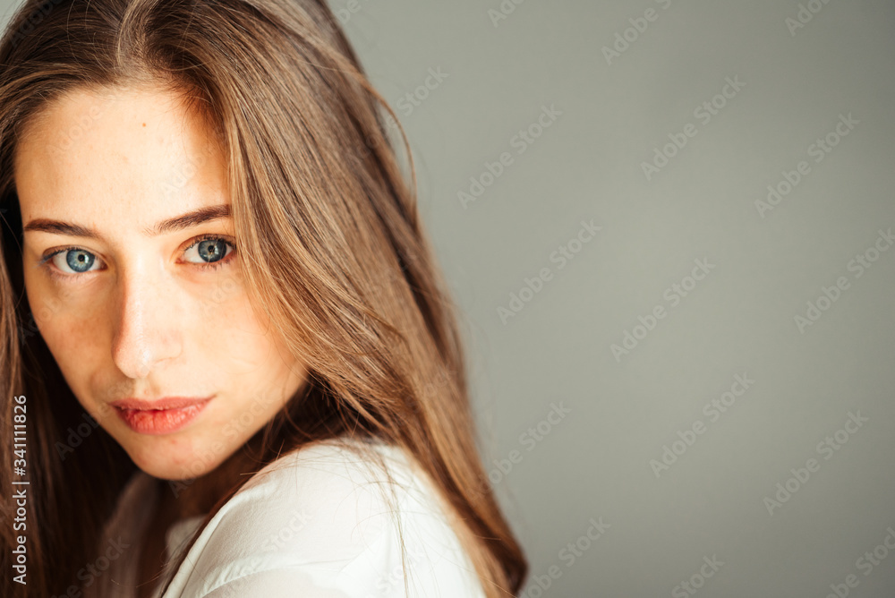 Serious girl with her hair in bright clothes on a gray background, close-up. Nude makeup, without retouching. Serious girl with her hair in bright clothes on a gray background, close-up. Nude makeup, without retouching.
