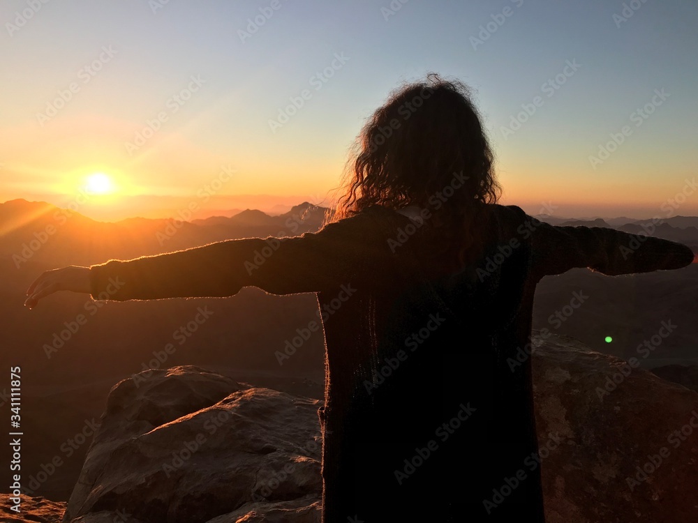silhouette of a woman standing on a rock sunrise