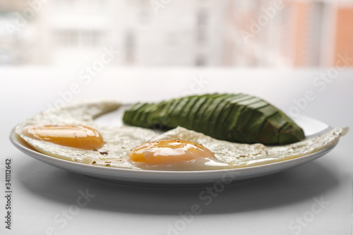 Scrambled eggs with avocado and specialy on a white plate on a white background, closeup photo