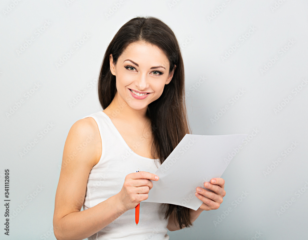 Happy smiling casual woman holding the paper and pen and ready to write successful agreement on blue background. Closeup Happy smiling casual woman holding the paper and pen and ready to write successful agreement on blue background. Closeup