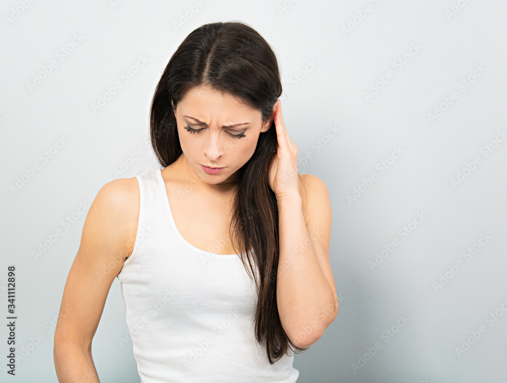 Beautiful unhappy woman holding the head with headache. Corona virus. Studio portrait on blue background Beautiful unhappy woman holding the head with headache. Corona virus. Studio portrait on blue background