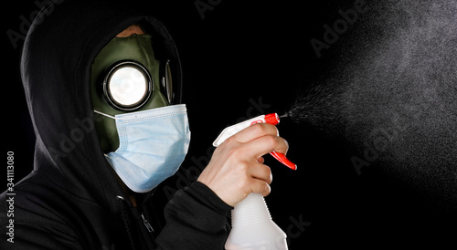 Person wearing old hazmat style gas mask and medical mask cleaning with spray bottle.