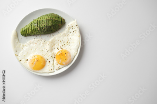 Scrambled eggs with avocado and specialy on a white plate on a white background with blank copy space, top view photo