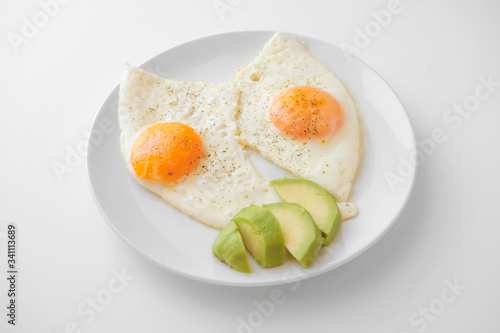 Scrambled eggs with avocado and specialy on a white plate on a white background. Close-up, top view photo