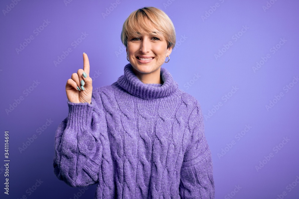 Young blonde woman with short hair wearing winter turtleneck sweater over purple background pointing finger up with successful idea. Exited and happy. Number one. Young blonde woman with short hair wearing winter turtleneck sweater over purple background pointing finger up with successful idea. Exited and happy. Number one.