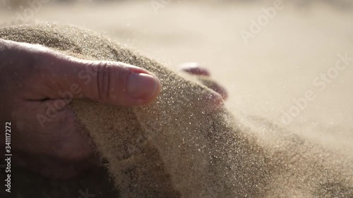 Two hands raising hot sand up and streaming it down in a desert in sunny spring