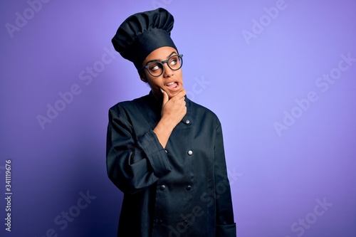 Young african american chef girl wearing cooker uniform and hat over purple background Thinking worried about a question, concerned and nervous with hand on chin