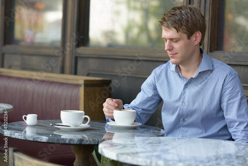 Young blond businessman thinking at the coffee shop outdoors