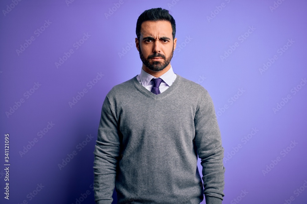 Handsome businessman with beard wearing casual tie standing over purple background skeptic and nervous, frowning upset because of problem. Negative person.