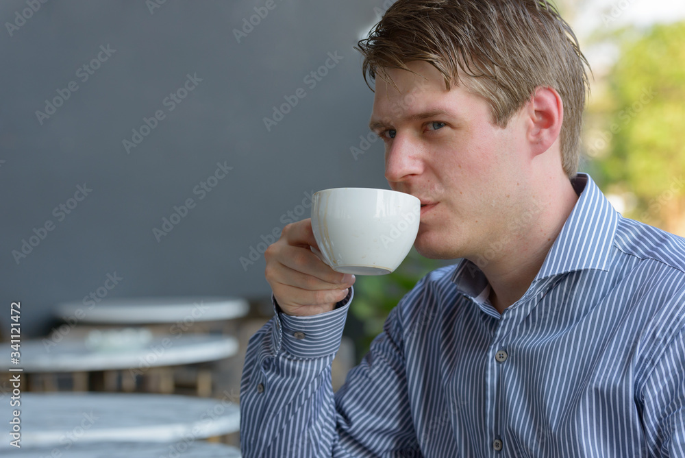 Face of young handsome blond businessman at the coffee shop outdoors Face of young handsome blond businessman at the coffee shop outdoors