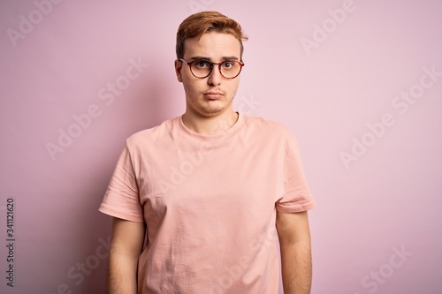 Young handsome redhead man wearing casual t-shirt standing over isolated pink background depressed and worry for distress, crying angry and afraid. Sad expression. © Krakenimages.com
