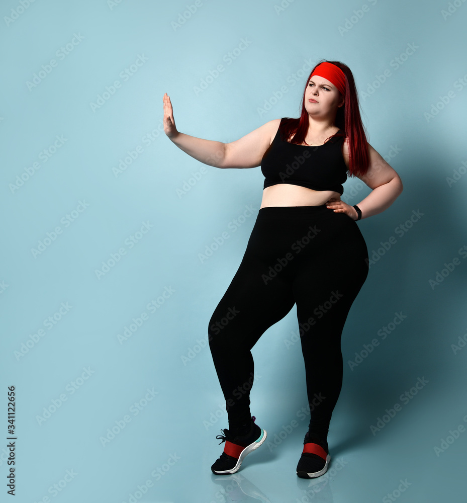 Overweight ginger girl in red headband, black top, leggings
