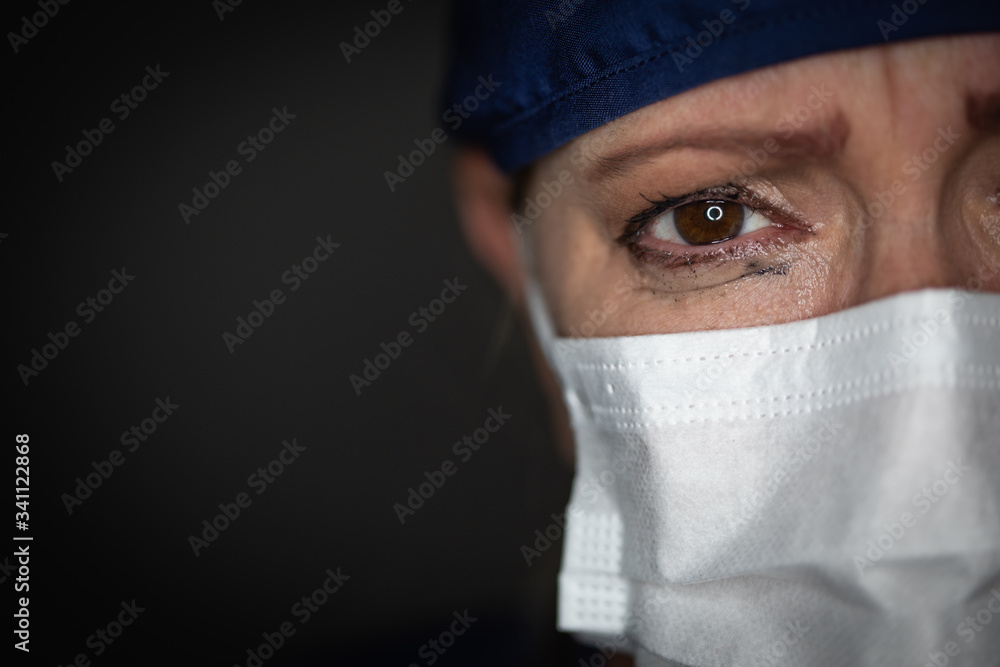 Tearful Stressed Female Doctor or Nurse Wearing Medical Face Mask on Dark Background Tearful Stressed Female Doctor or Nurse Wearing Medical Face Mask on Dark Background