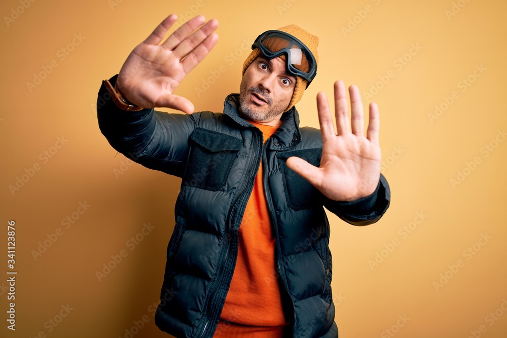 Young handsome skier man skiing wearing snow sportswear using ski goggles doing frame using hands palms and fingers, camera perspective Young handsome skier man skiing wearing snow sportswear using ski goggles doing frame using hands palms and fingers, camera perspective