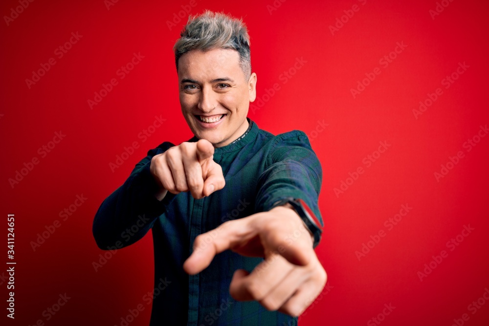 Young handsome modern man wearing elegant green shirt over red isolated background pointing to you and the camera with fingers, smiling positive and cheerful Young handsome modern man wearing elegant green shirt over red isolated background pointing to you and the camera with fingers, smiling positive and cheerful