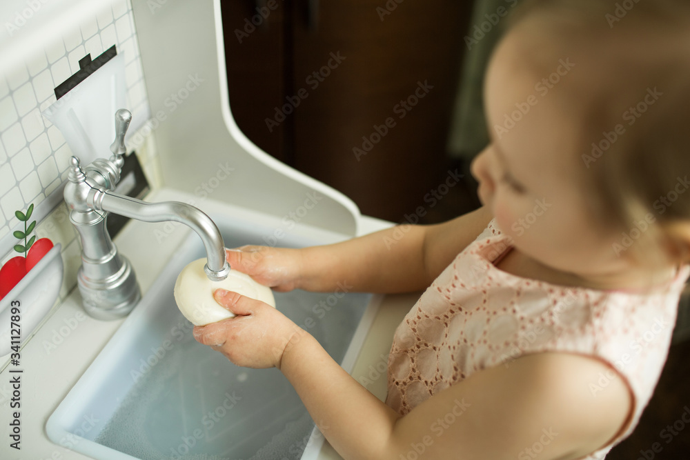 .little girl washes her hands with soap in the children's kitchen. hand hygiene rules .little girl washes her hands with soap in the children's kitchen. hand hygiene rules
