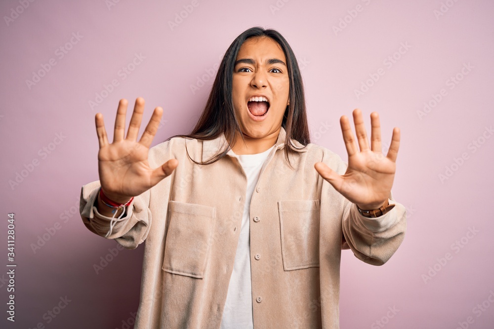 Young beautiful asian woman wearing casual shirt standing over pink background afraid and terrified with fear expression stop gesture with hands, shouting in shock. Panic concept. Young beautiful asian woman wearing casual shirt standing over pink background afraid and terrified with fear expression stop gesture with hands, shouting in shock. Panic concept.