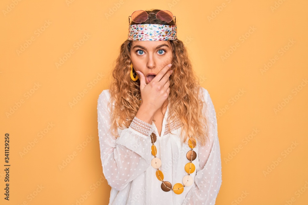 Young beautiful blonde hippie woman with blue eyes wearing sunglasses and accessories Looking fascinated with disbelief, surprise and amazed expression with hands on chin Young beautiful blonde hippie woman with blue eyes wearing sunglasses and accessories Looking fascinated with disbelief, surprise and amazed expression with hands on chin