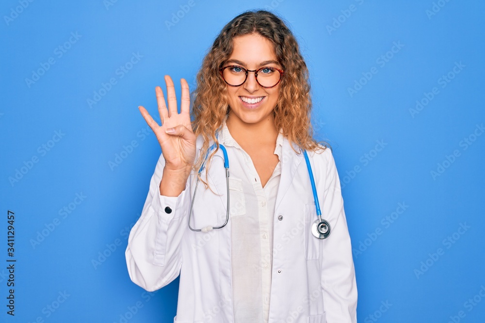 Young beautiful blonde doctor woman with blue eyes wearing coat and stethoscope showing and pointing up with fingers number four while smiling confident and happy. Young beautiful blonde doctor woman with blue eyes wearing coat and stethoscope showing and pointing up with fingers number four while smiling confident and happy.