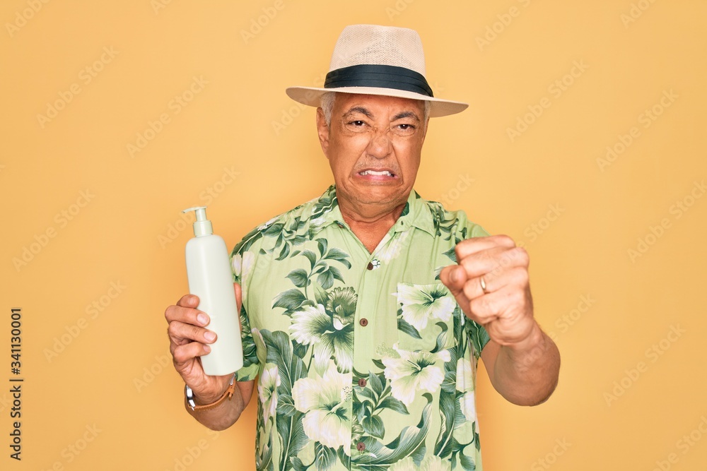 Middle age senior grey-haired man wearing summer hat holding sun protection cream annoyed and frustrated shouting with anger, crazy and yelling with raised hand, anger concept Middle age senior grey-haired man wearing summer hat holding sun protection cream annoyed and frustrated shouting with anger, crazy and yelling with raised hand, anger concept