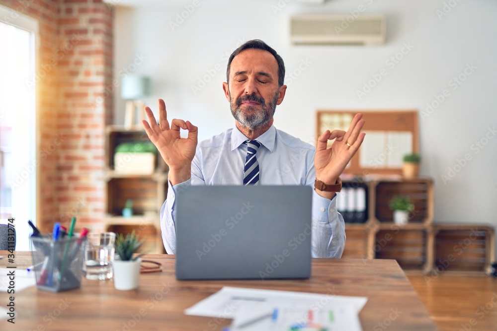 Middle age handsome businessman wearing tie sitting using laptop at the office relax and smiling with eyes closed doing meditation gesture with fingers. Yoga concept. - obrazy, fototapety, plakaty 